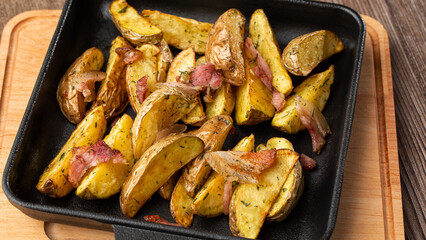 Delicious Fried Potato Bratkartoffeln With Bacon and Onion close up in the black plate on the table.