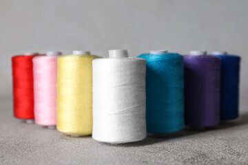 Sewing threads on grey background, closeup