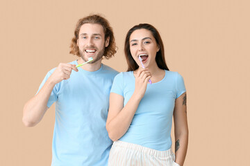Young couple brushing teeth on beige background