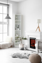 Stylish interior of light room with fireplace and shelf unit near white wall