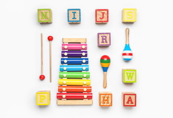 Wooden cubes with rattles and xylophone on white background