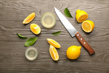 Composition with ripe lemons, bowls of juice and knife on dark wooden background