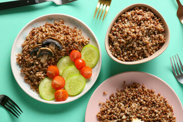 Plates of tasty buckwheat porridge on turquoise background, top view