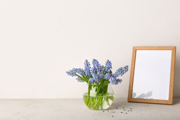 Vase with beautiful Muscari flowers and photo frame on light table