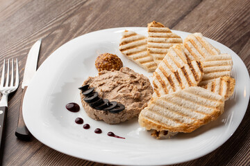 Liver meat pate spread with grilled white bread on a wooden background, breakfast, close-up, no people, selective focus, pasticcio, pastete