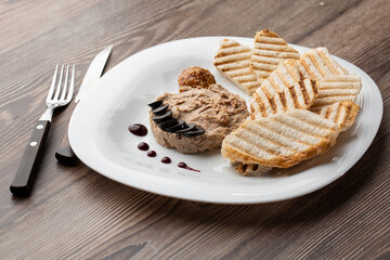 Liver meat pate spread with grilled white bread on a wooden background, breakfast, close-up, no people, selective focus, pasticcio, pastete