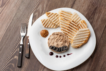 Liver meat pate spread with grilled white bread on a wooden background, breakfast, close-up, no people, selective focus, pasticcio, pastete