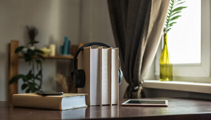 A stack of books with headphones and tablets on the table. The concept of modern technological education and the study of books