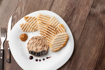 Liver meat pate spread with grilled white bread on a wooden background, breakfast, close-up, no people, selective focus, pasticcio, pastete