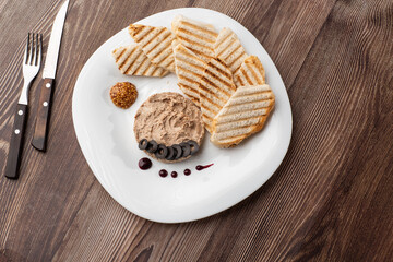 Liver meat pate spread with grilled white bread on a wooden background, breakfast, close-up, no...