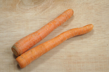 Two orange carrots on a wooden background