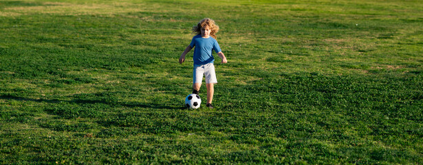 Soccer kid boy playing football. Child boy play football on outdoor field. Children score goal at...