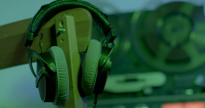 Headphones close-up on the background of the spinning reels of a retro turntable. Green light, no people. 