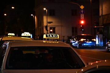 Drei Taxen stehen am Taxi-Stand, beleuchtetes Taxilogo in der Nacht, Taxischild in Frankfurt, Hessen, Deutschland