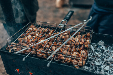 Pickled champignons are fried on coals. Barbecue, grill for frying, charcoal, smoke from the fire. Outdoor recreation, cooking outside.