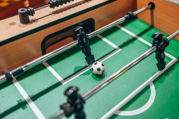 Table football. Kicker. A black figure from a table football. Green field. The goalkeeper defends his goal.