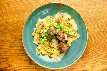 Italian recipe Pasta tortilloni with green pea, mint leaves, cheece, smoked bacon and cheese. Top view, blue background