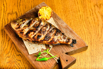 Big fish dorado with lemon and sauce on wooden table in luxury restaurant