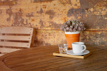 white coffee cup and glass of water on vintage wooden table and flower pot