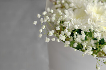bouquet of white chrysanthemums and gypsophila wrapped in craft paper. delicate bouquet of white flowers. Spring bouquet of white chrysanthemums close-up.