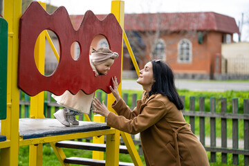 Child education concept. Mom and daughter are playing on the playground.