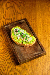 Whole grain bread toast with avocado on a wooden board
