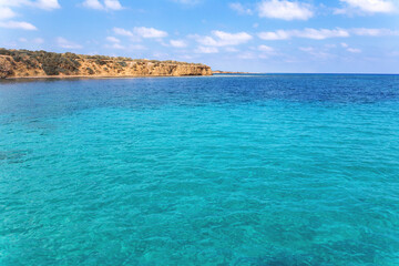 Fototapeta premium View of rocky coast turquoise sea waters on a sunny day with blue sky. Blue lagoon. Destination scenics seascape. Travel and adventure. Cyprus. Mediterrenian. No people