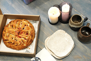 Still life with fruit pie, ceramic cups and plates on a wooden table.