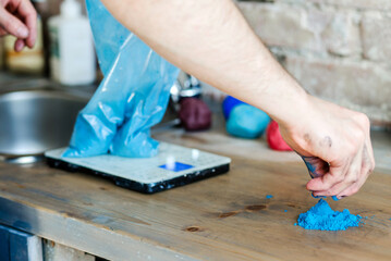 The potter weighs on the scales the amount of dye necessary for kneading with clay