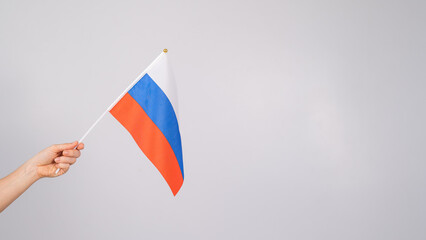 Woman holding a small flag of the Russian Federation on a white background. 