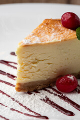 Cheesecake New York or classic cheesecake with caramel. Closeup view. Tasty breakfast. Piece of cake on white plate, on wooden background.