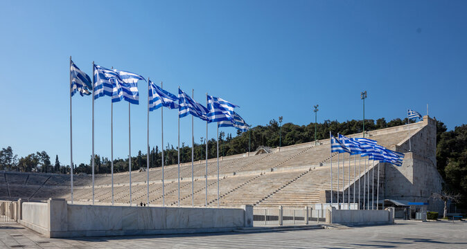 Athens, Greece. The Panathenaic Stadium or Kallimarmaro. Ancient marble arena. Greek flags waving