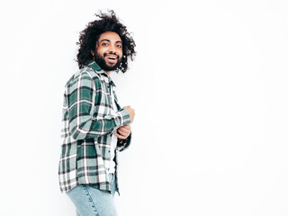 Handsome smiling hipster  model.Sexy unshaven Arabian man dressed in summer shirt and jeans clothes. Fashion male with long curly hairstyle posing near wall in studio. Isolated on white