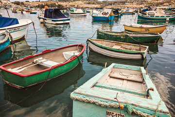 Fototapeta na wymiar Colorful boats at Maltese fishing village Marsaxlokk, Malta