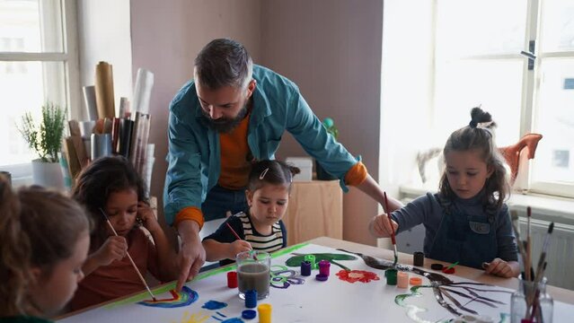 Little kids working on project with teacher during creative art and craft class at school.