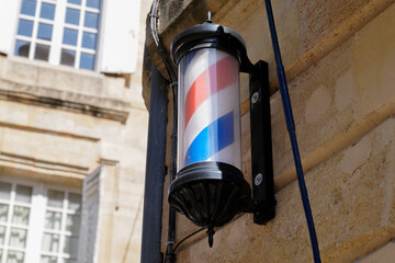 Fototapeta na wymiar barber pole shop brand sign in wall facade entrance hairdresser in chrome white red blue colors