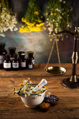 Assorted natural medical herbs and mortar on wooden table background