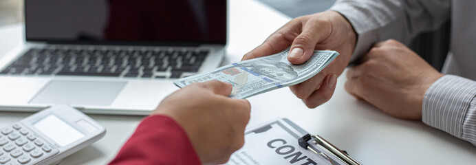 Shaking hands with congratulations on an evil plan, Businessmen give dollars to bribe employees in signing contracts to buy illegal land and real estate, corruption and Bribery concept.