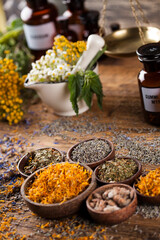Herbs, berries and flowers with mortar, on wooden table background