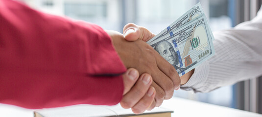 Shaking hands with congratulations on an evil plan, Businessmen give dollars to bribe employees in signing contracts to buy illegal land and real estate, corruption and Bribery concept.