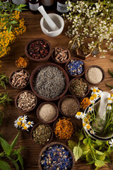Alternative medicine, dried herbs and mortar on wooden desk background