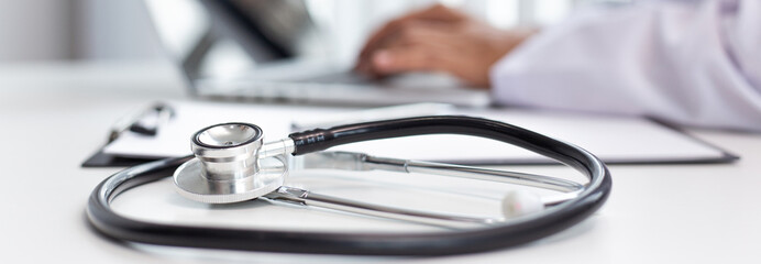 Doctor uses a laptop computer to record patient information and write it on a document to prepare for diagnosis in the room of a modern hospital, Emergency assistance and health care concept.