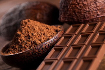 Chocolate bar, candy sweet, cacao beans and powder on wooden background