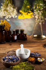Herbs, berries and flowers with mortar, on wooden table background