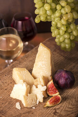 Cheese plate served with grapes, melon, figs, crackers, nuts and white wine on a wooden table