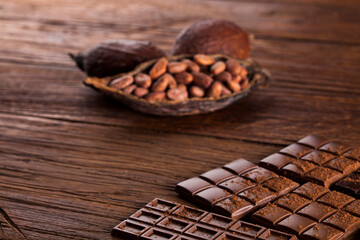 Dark homemade chocolate bars and cocoa pod on wooden