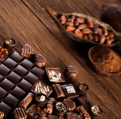 Chocolate bars and pralines on wooden background