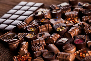 Chocolate bars and pralines on wooden background
