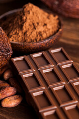 Chocolate bar, candy sweet, cacao beans and powder on wooden background