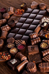 Chocolate bars and pralines on wooden background